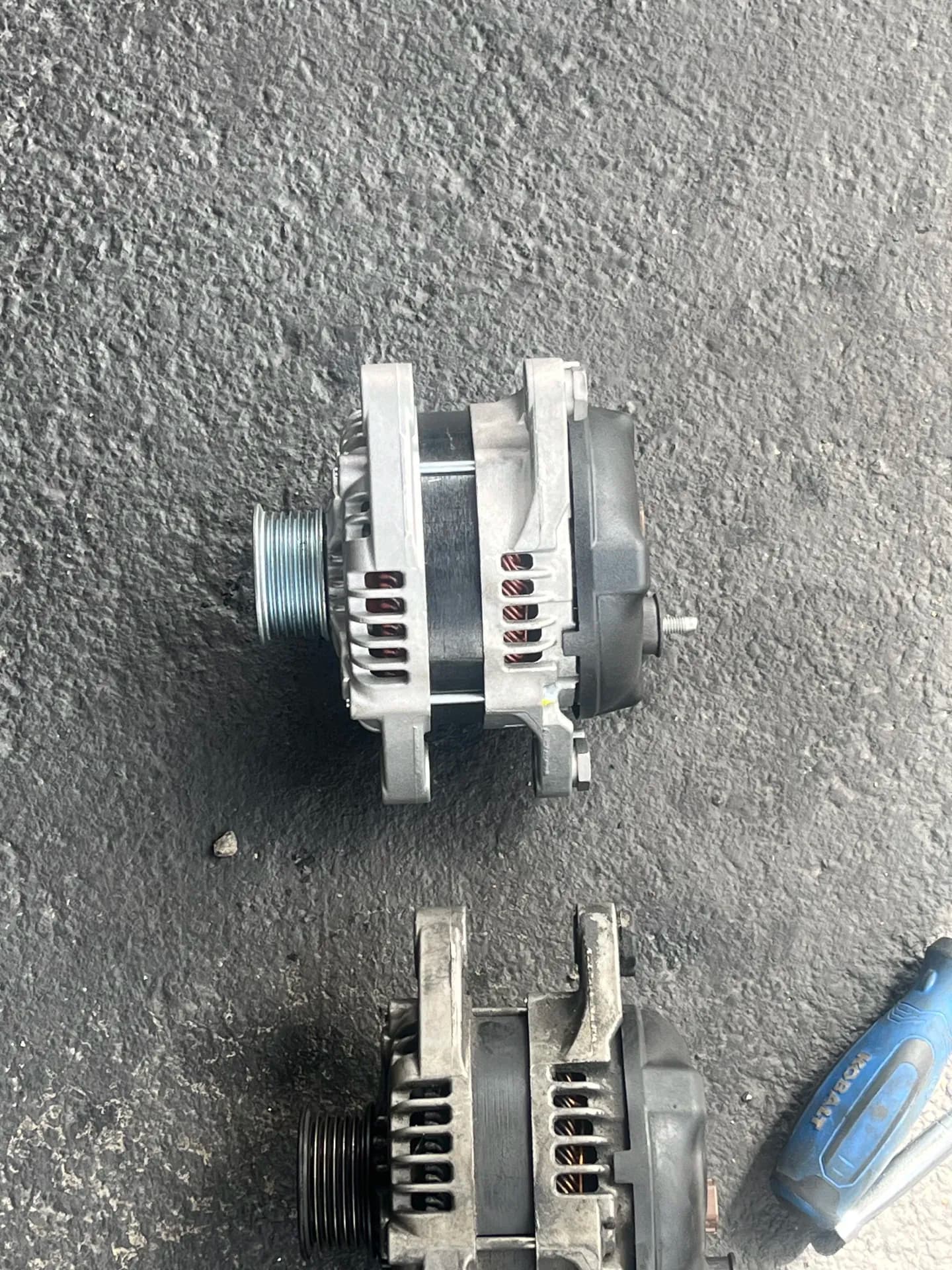 Replacement alternators compared during a charging-system repair